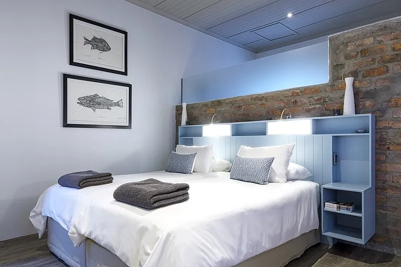 Modern bedroom with two beds blue headboard and fish artwork on the wall