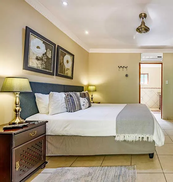 Cozy bedroom with a large bed bedside tables and floral artwork on the walls