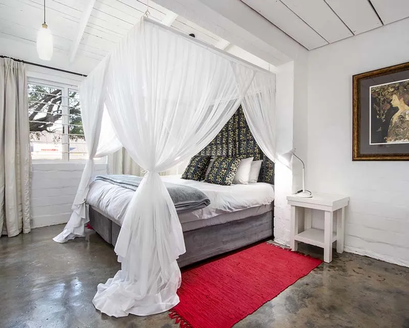 White canopy bed with patterned headboard in a bright modern bedroom