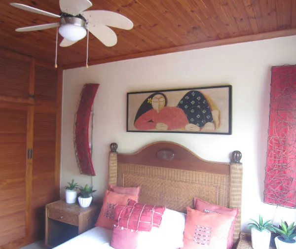 Wooden bedroom with ceiling fan artwork and potted plants on nightstand