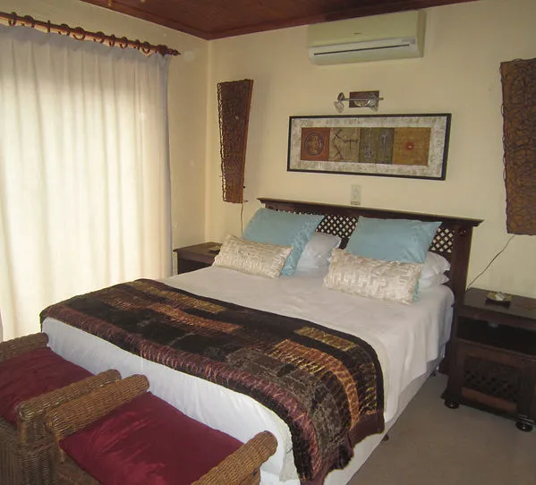 Cozy bedroom with a large bed wicker chairs and a wallmounted air conditioner