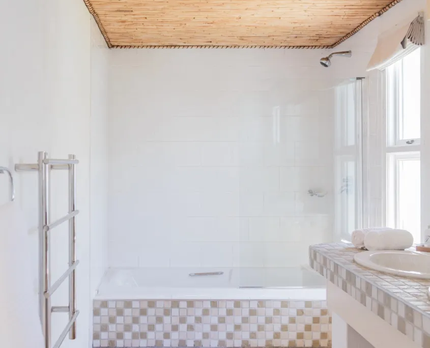 White bathroom with tiled walls bathtub towel rack and sink