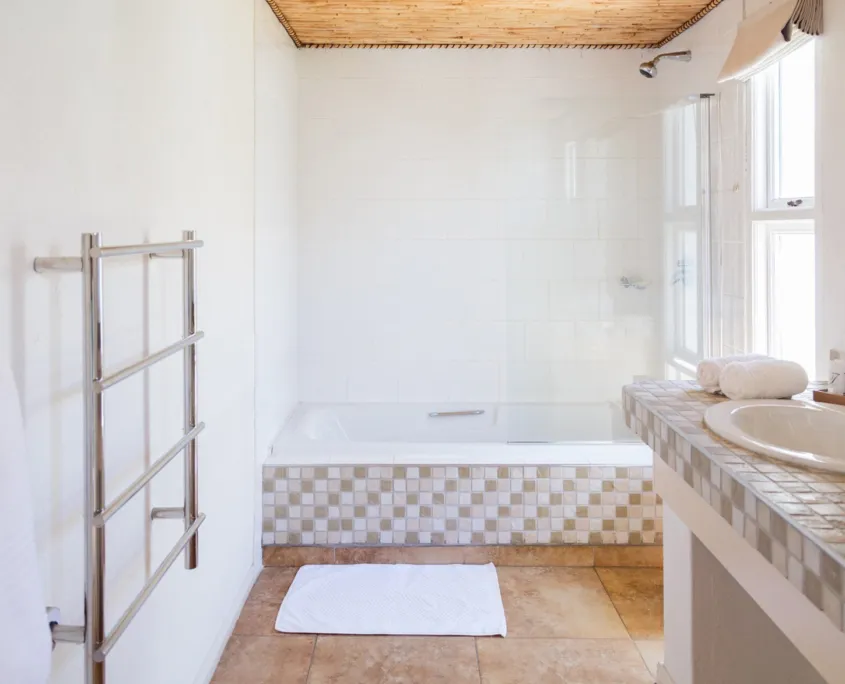 Modern bathroom with white bathtub towel rack and tiled floor