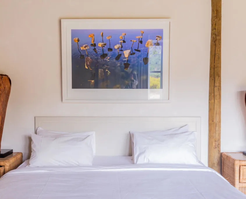 White bedroom with a large framed photo of water lilies above the bed