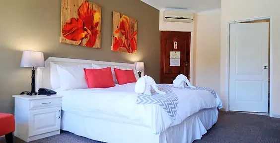 A neatly made bed with red pillows in a modern bedroom with artwork