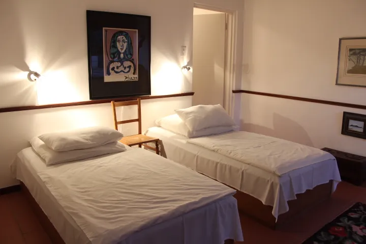 Two neatly made single beds in a simple artdecorated bedroom