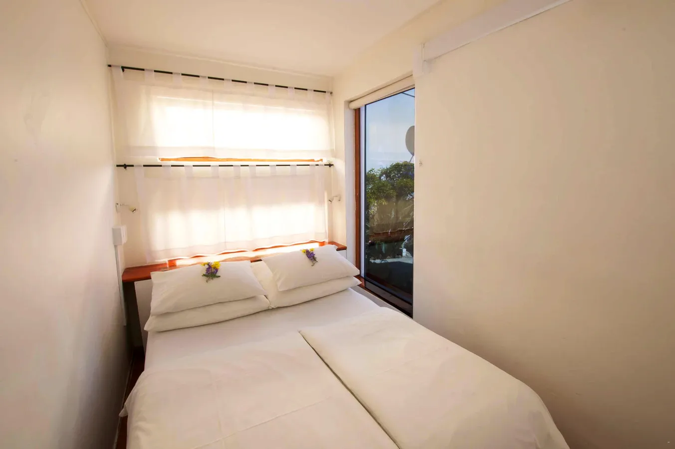 Small bedroom with twin beds white curtains and a window view