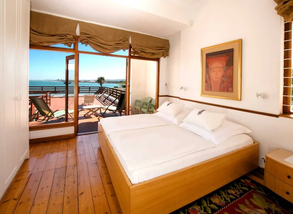 Bedroom with large bed open balcony doors ocean view and wooden floor