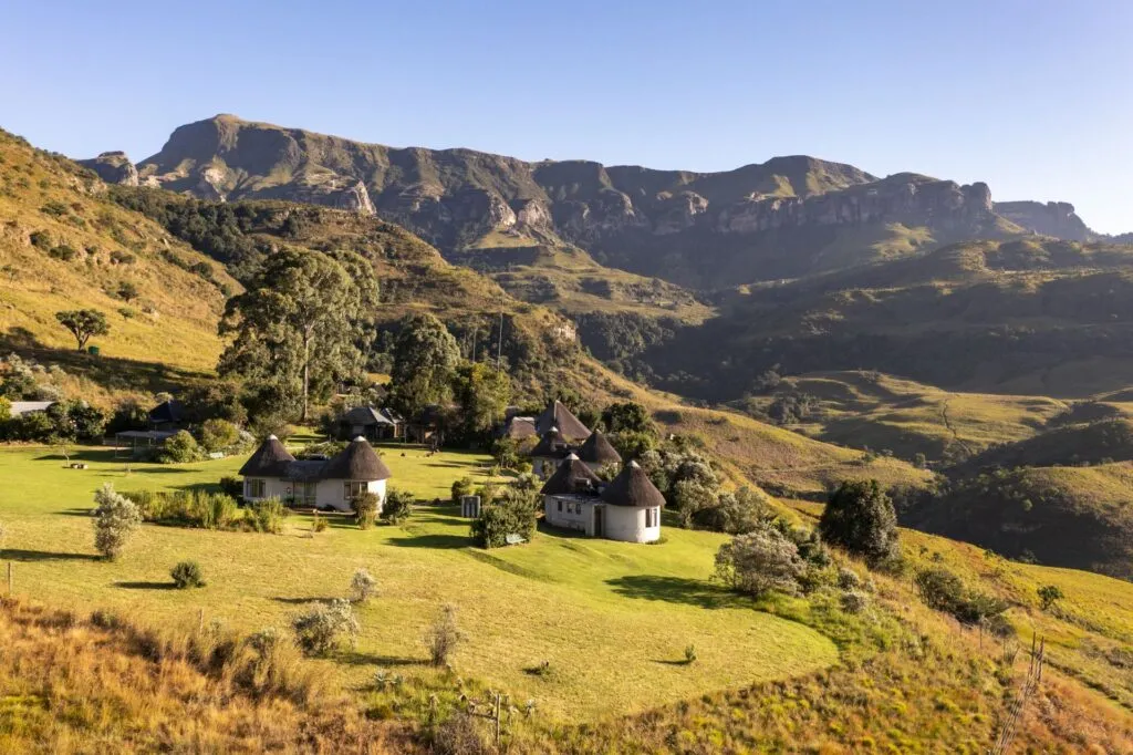 Traditional huts in a lush valley with mountains in the background