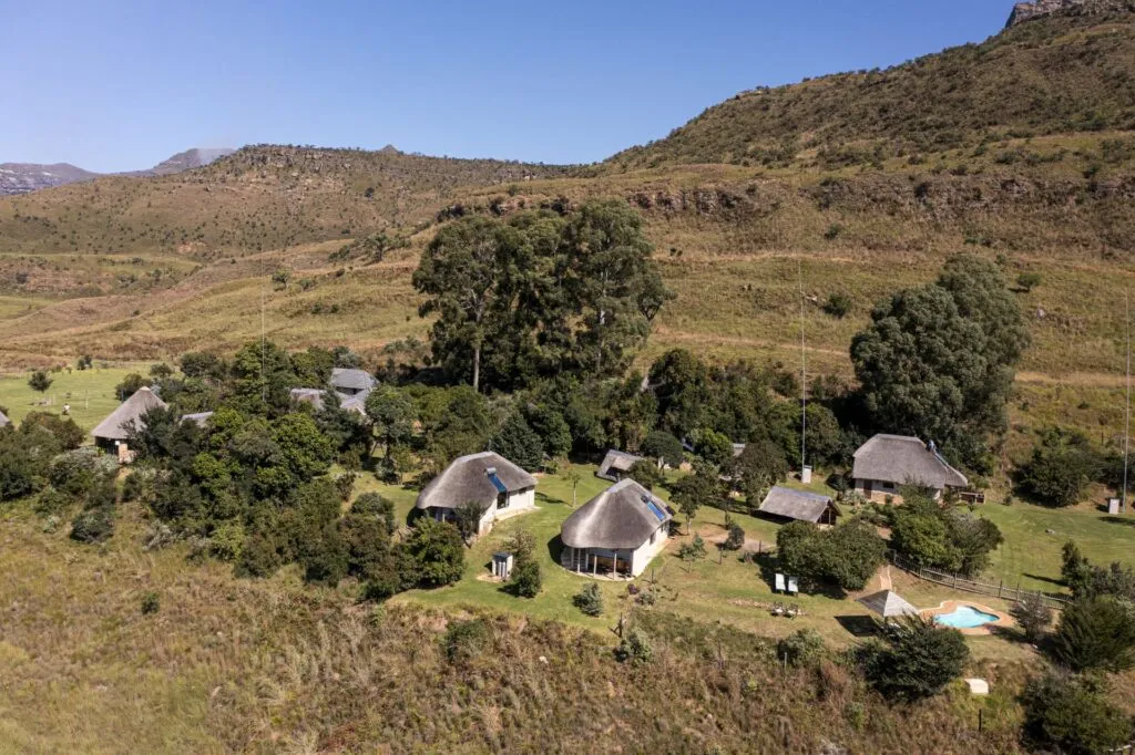 Thatchedroof huts in a lush hilly landscape under a clear blue sky