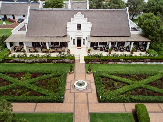 Aerial view of a large house with manicured gardens and pathways