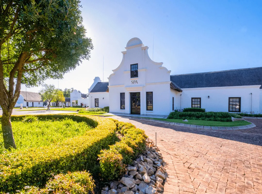 White building with SPA sign surrounded by greenery and a paved pathway