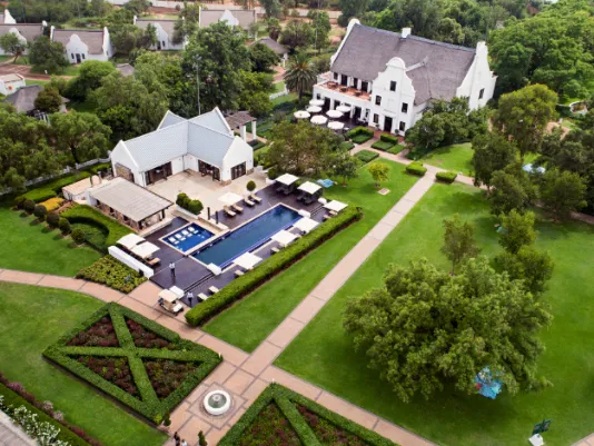 Aerial view of a large house with a pool and landscaped gardens