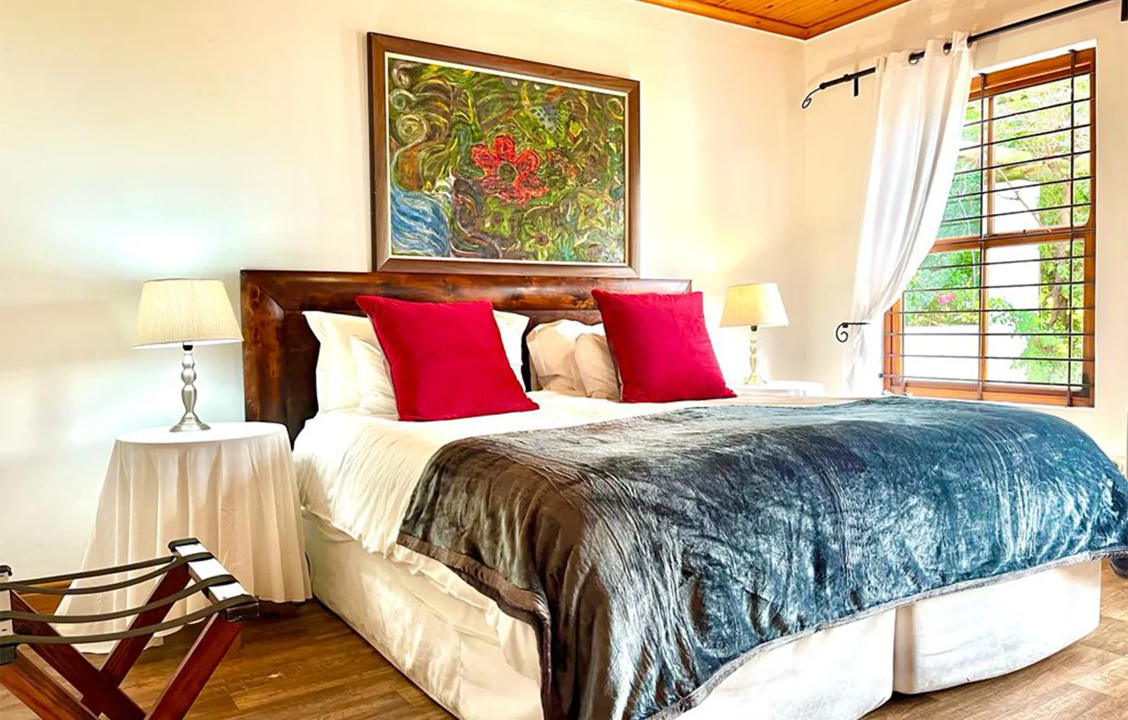 Cozy bedroom with large bed colorful painting and window with white curtains