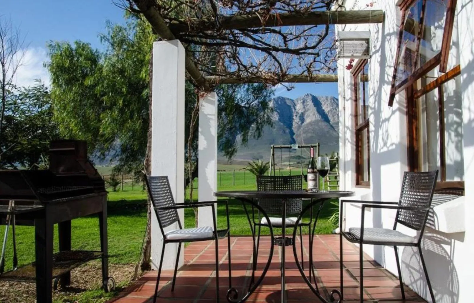 Patio with table chairs and BBQ grill overlooking mountains and greenery
