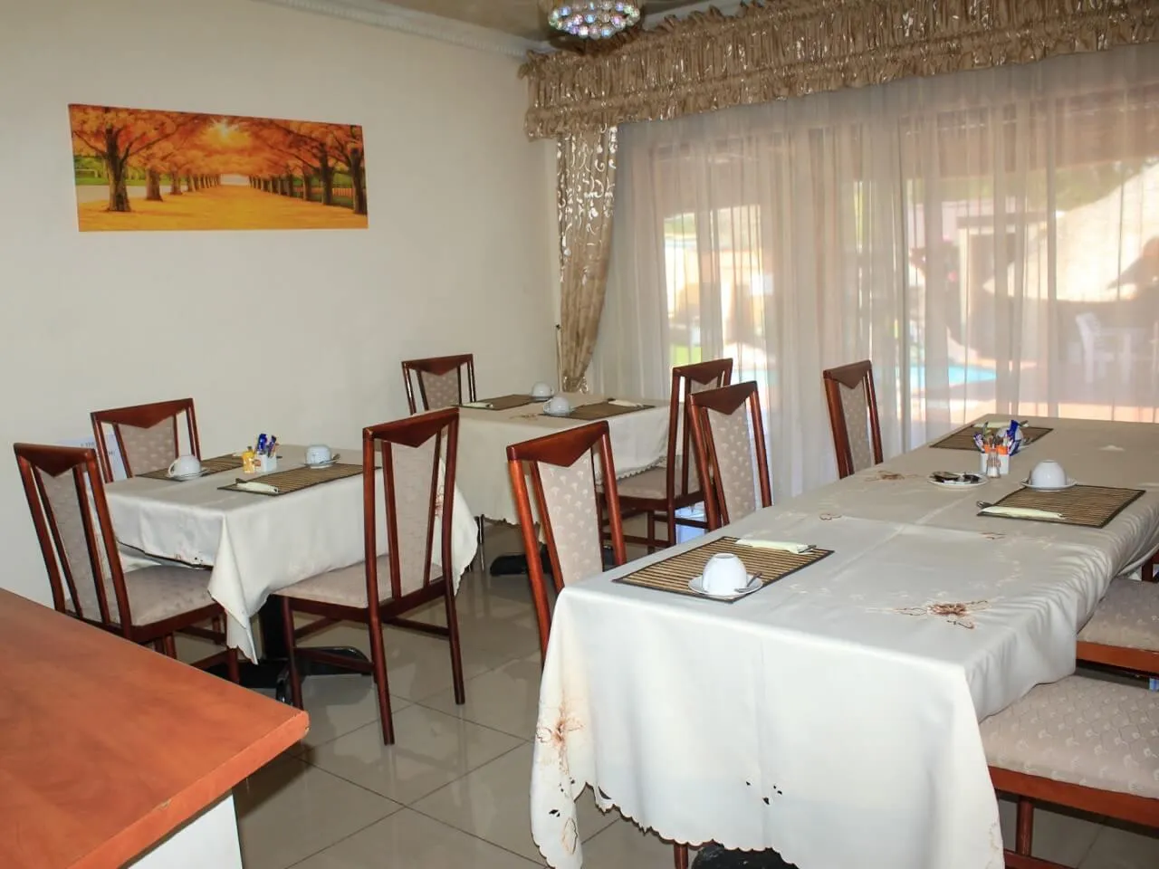 Dining area with tables chairs and a view of a garden through windows