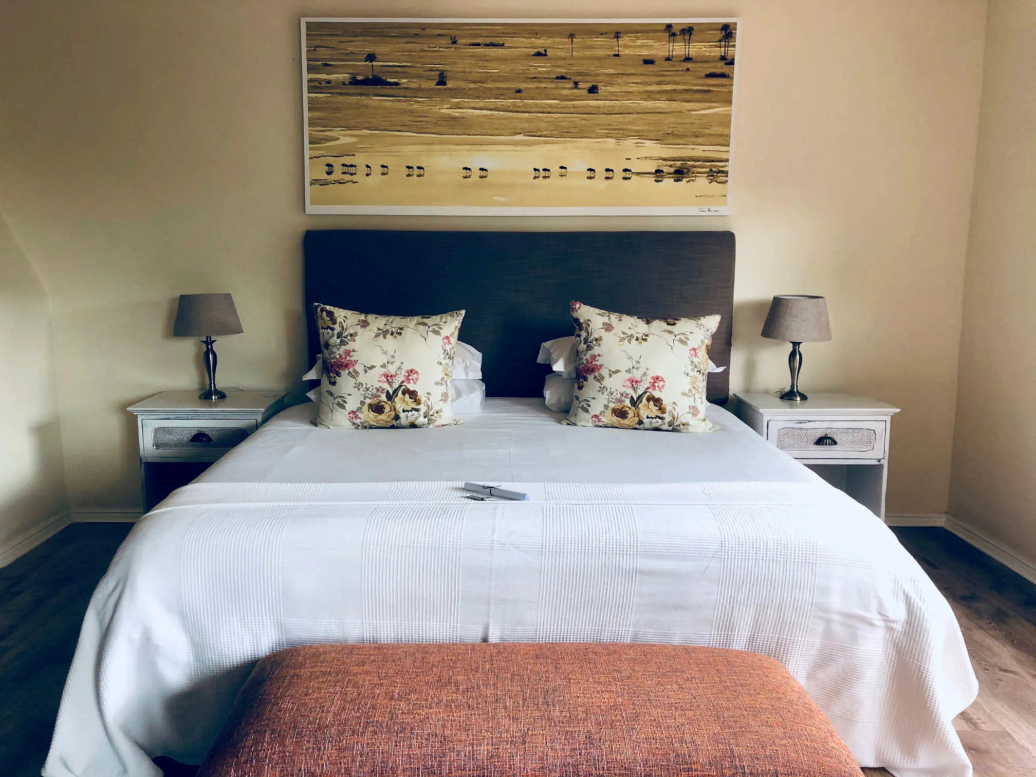 Neatly made bed with floral pillows nightstands and lamps in a bedroom