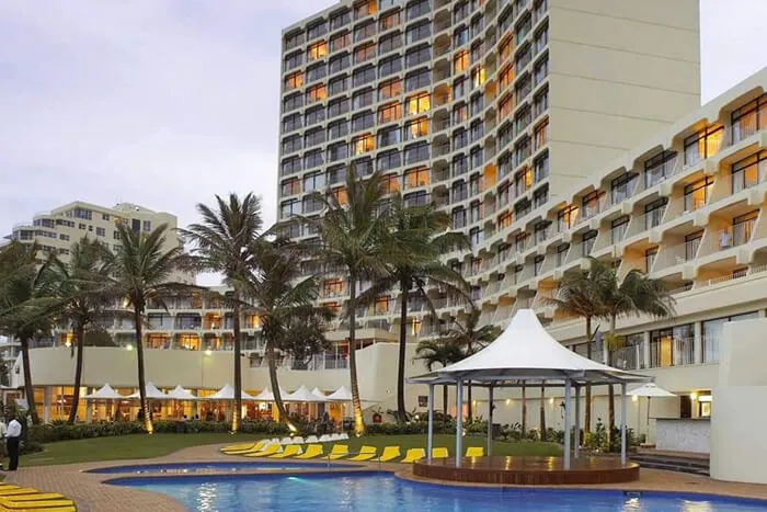 Hotel with pool palm trees and multistory building at sunset