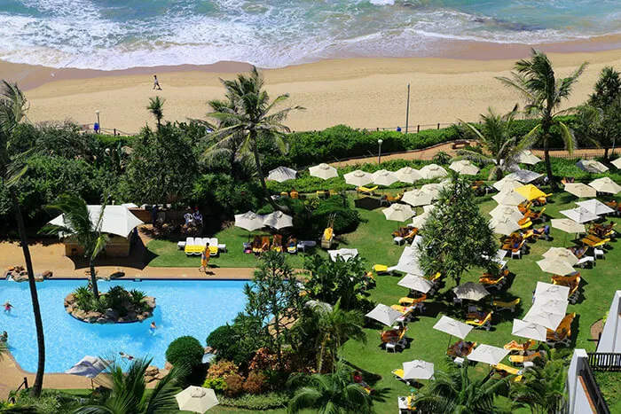Resort with pool lounge chairs umbrellas and beach in the background