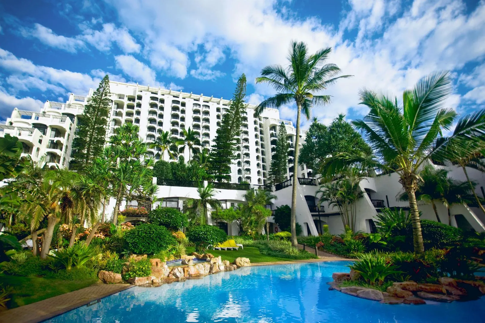 Tropical resort with large pool palm trees and white multistory building