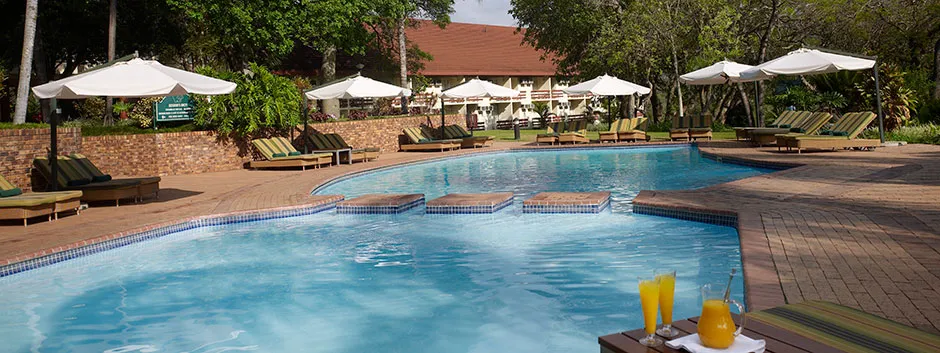 Swimming pool with lounge chairs umbrellas and drinks on a sunny day