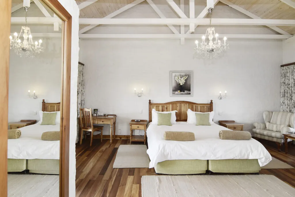 Wooden bed with white linens in a bright spacious bedroom with wooden floors