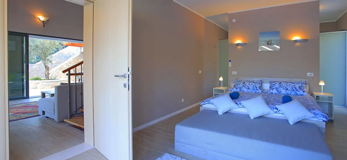 Modern bedroom with a large bed open door to a hallway with outdoor view