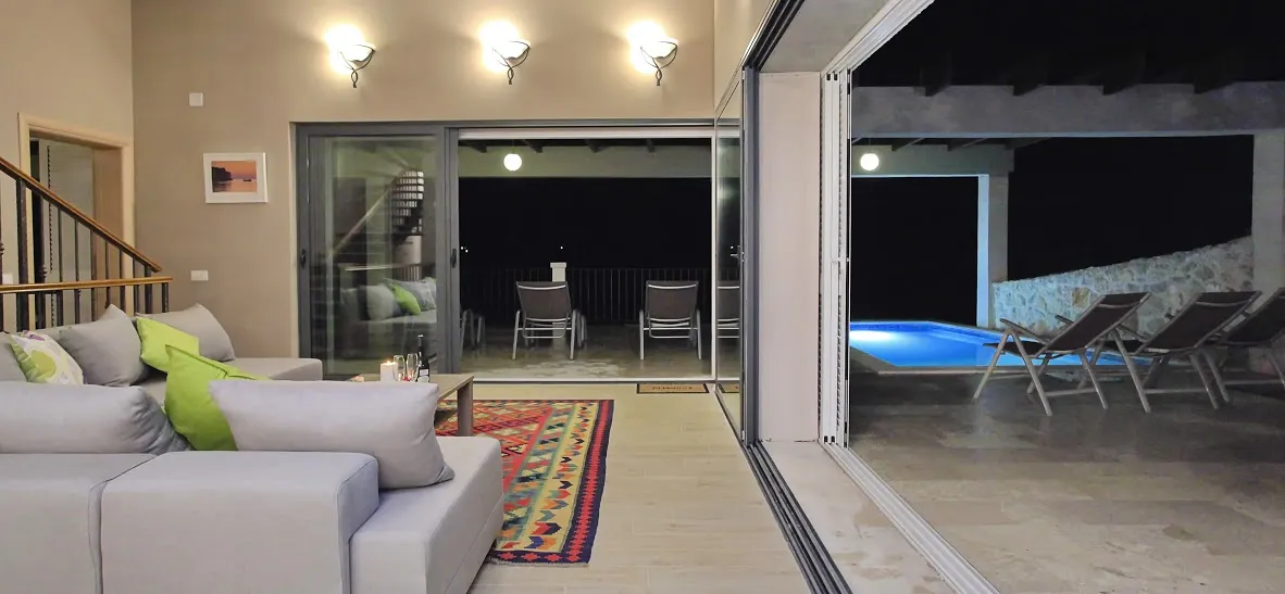Modern living room with open sliding doors leading to a pool area at night