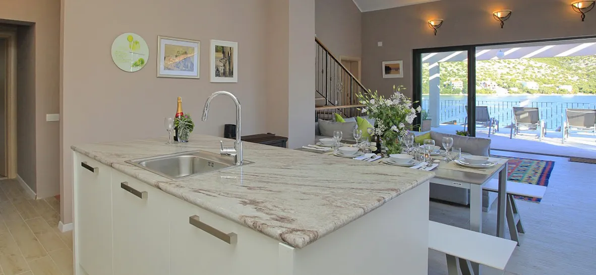 Modern kitchen island with marble countertop open to dining area with sea view