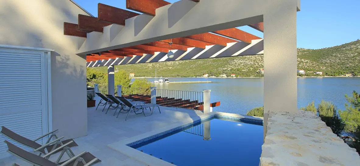Modern villa with pool overlooking a lake and hills with lounge chairs