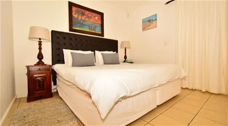 Bedroom with a large bed two bedside tables lamps and beachthemed artwork