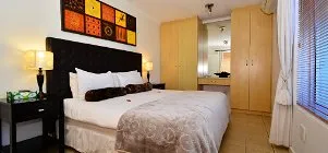 Modern bedroom with large bed wooden wardrobes and colorful wall art