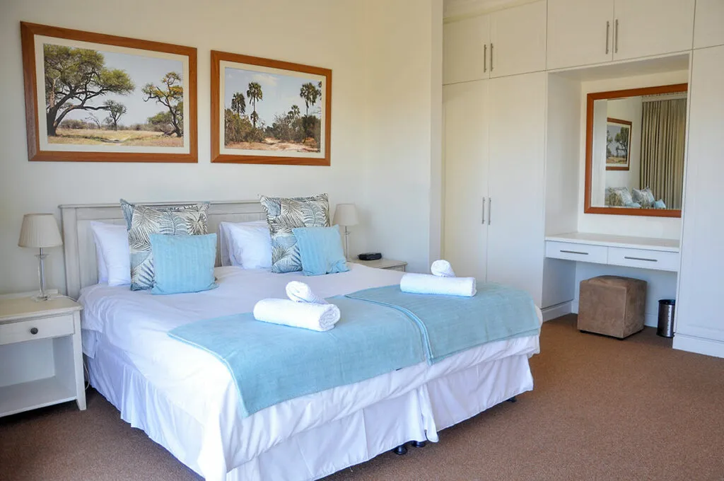 Bedroom with large bed blue pillows and wall art next to a mirror