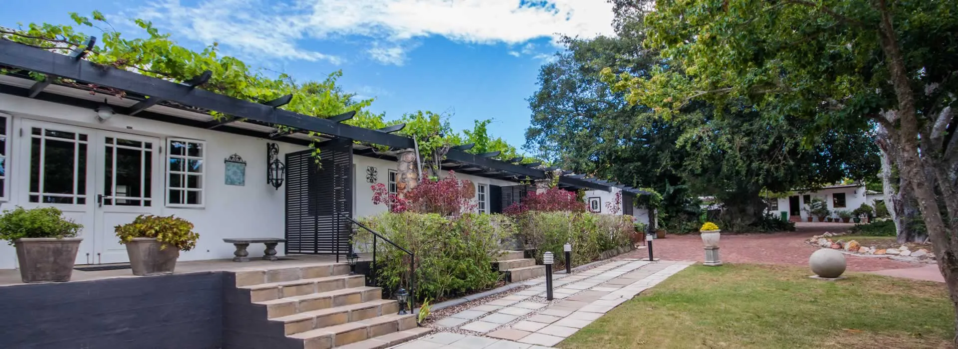 White building with steps plants and pathway in a garden setting