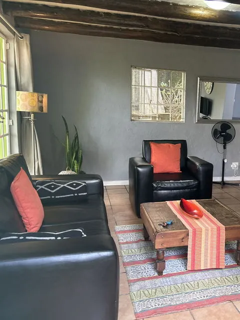 Black leather furniture in a cozy living room with a striped rug