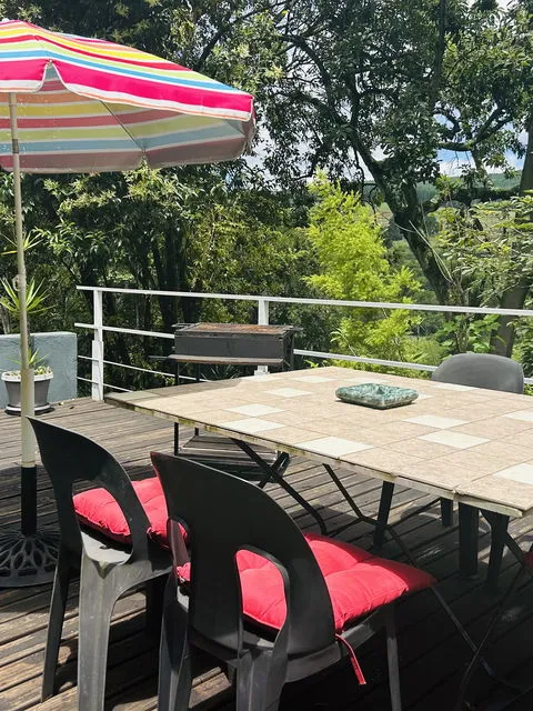 Two chairs with red cushions at a tiled table under a colorful umbrella