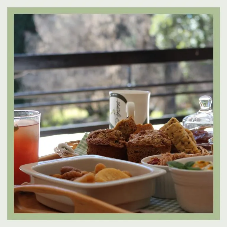 A breakfast spread with muffins fruits and drinks on a balcony