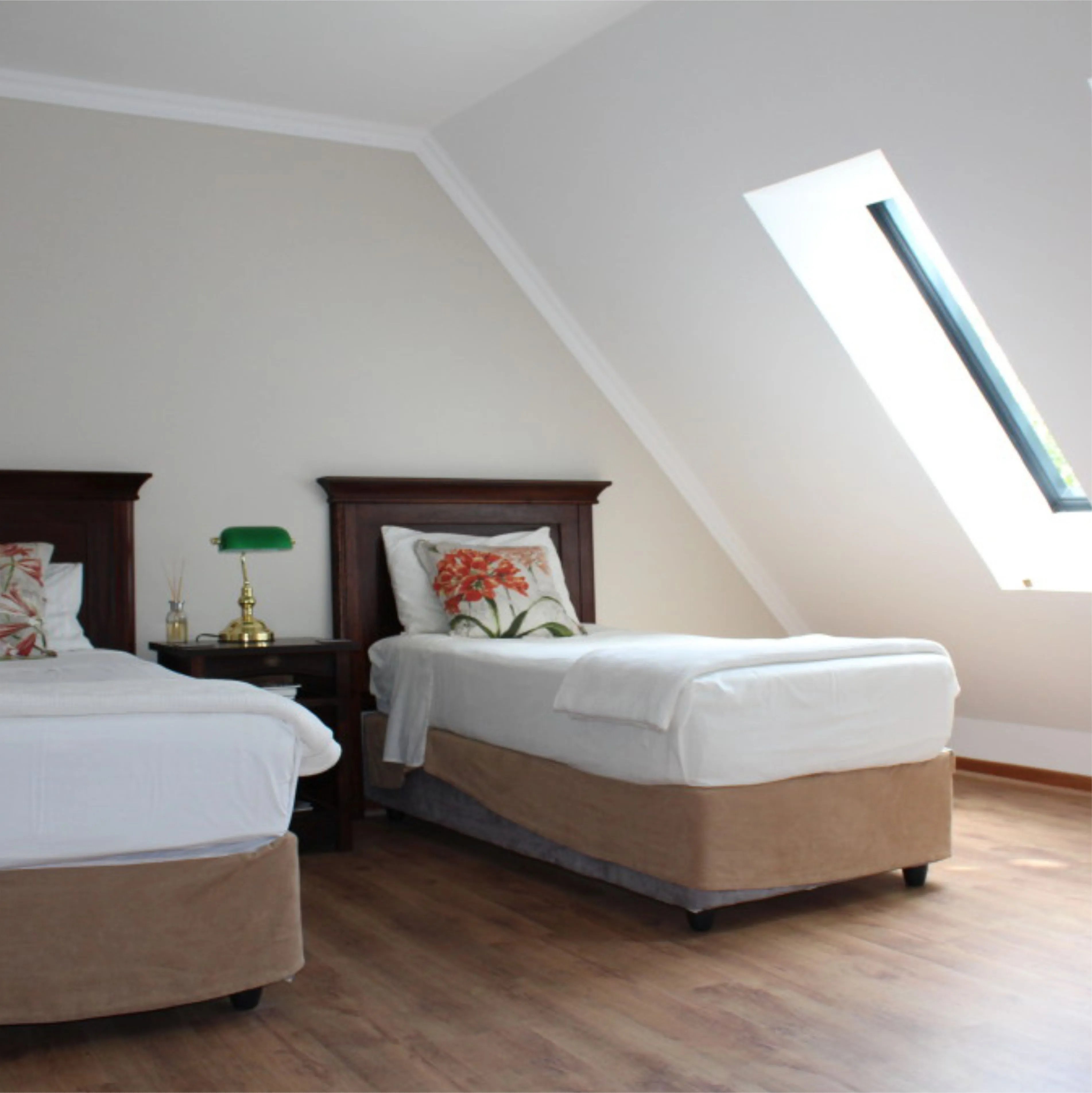 Two single beds in a bedroom with wooden floor and slanted ceiling