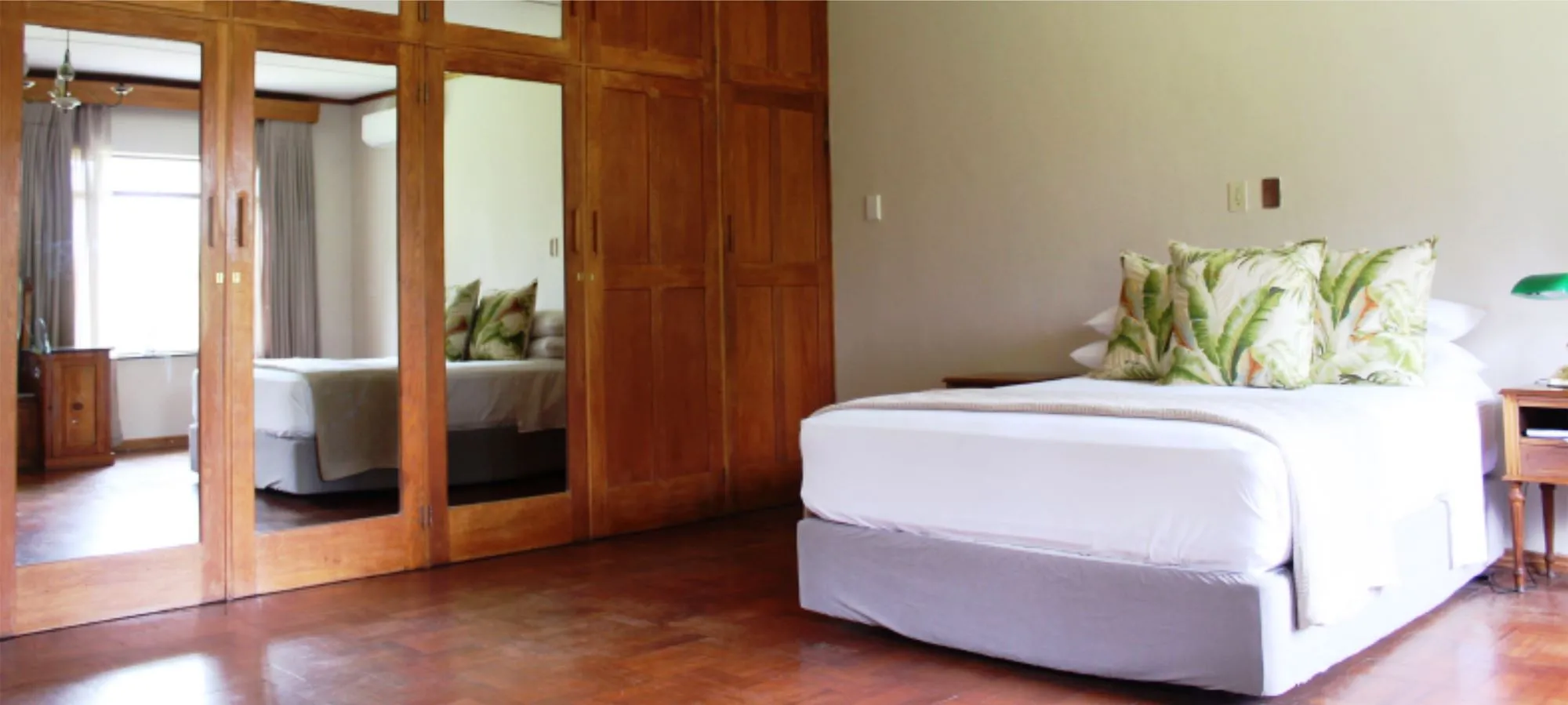 Wooden bedroom with large bed mirrored wardrobe and wooden floor