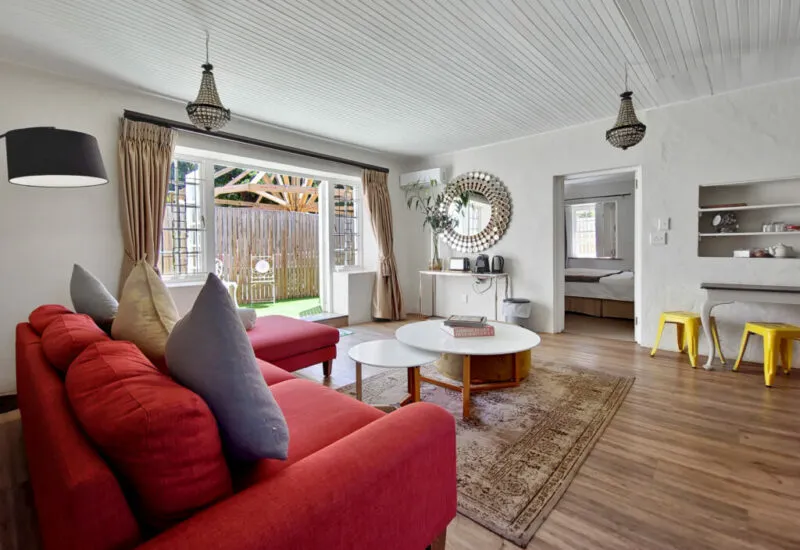 Bright living room with red sofa wooden floor and garden view through glass doors