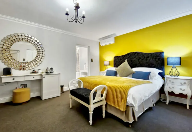 Bedroom with yellow wall large bed mirror and bedside tables with lamps