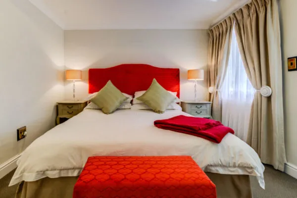 Red and white bedroom with a large bed two nightstands and a window