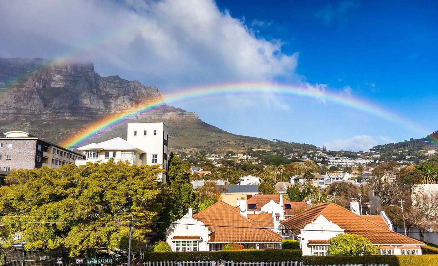 Rainbow over residential area with mountain in background on a sunny day