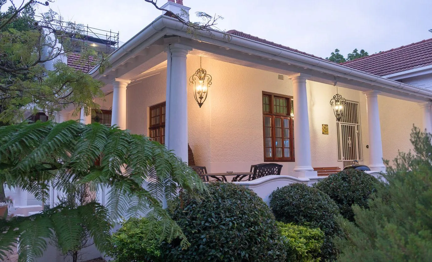 White house with columns lit windows and surrounding greenery at dusk