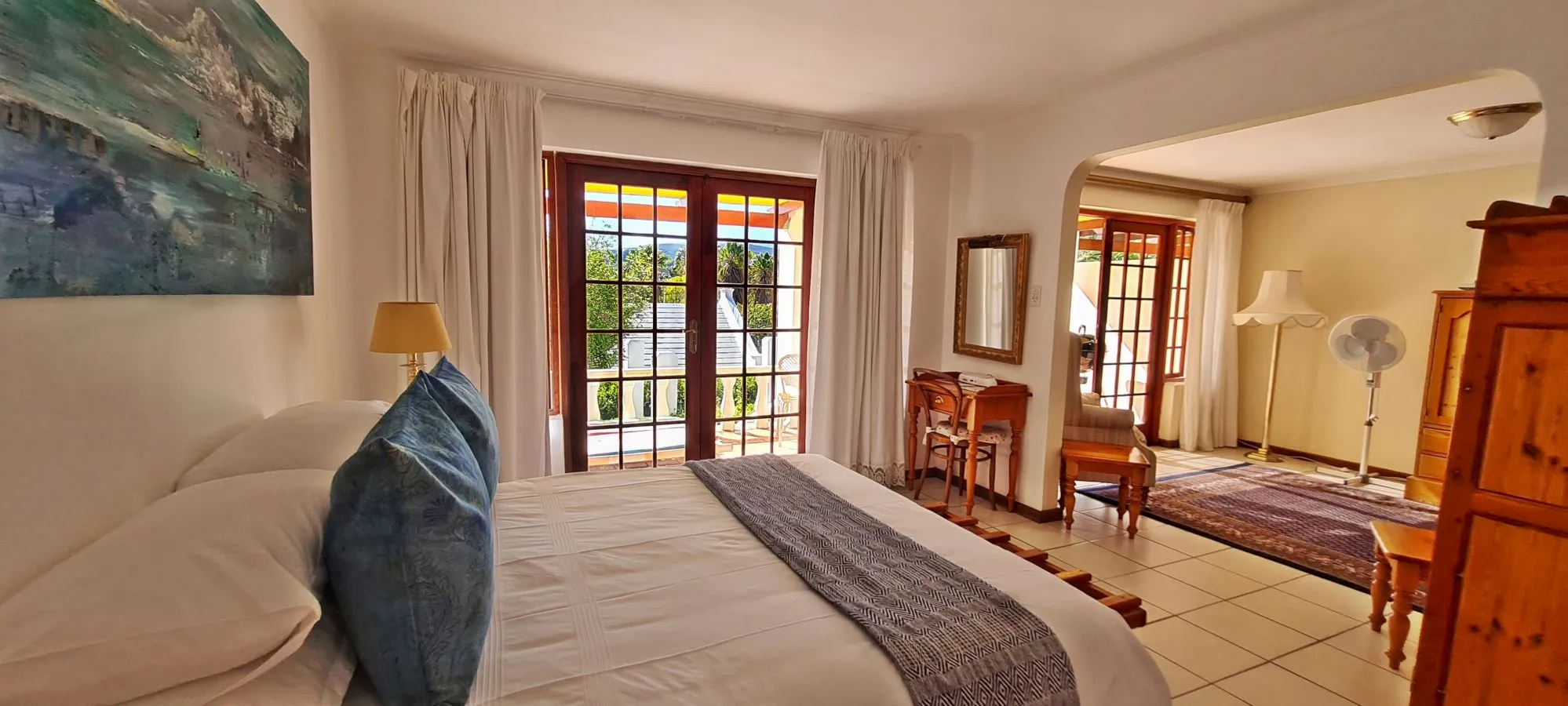 Bedroom with large bed wooden furniture and glass doors to a garden