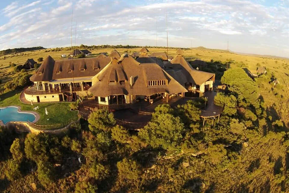 Large luxurious house with pool surrounded by greenery and open fields