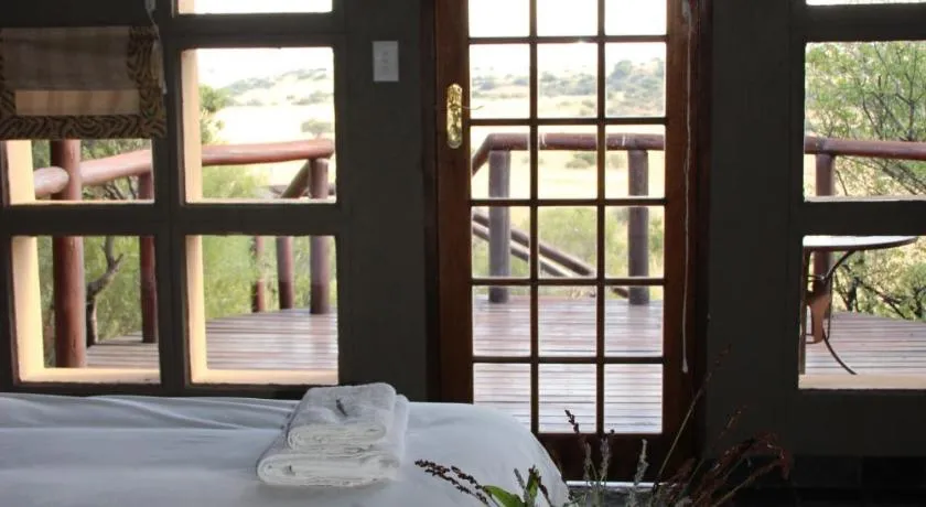 Bed with towels in a room overlooking a wooden deck and outdoor view