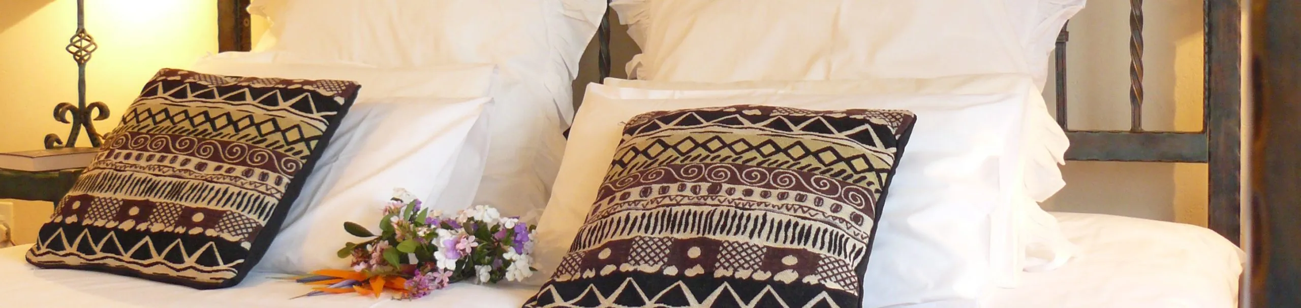 Decorative pillows on a bed with a bouquet of flowers