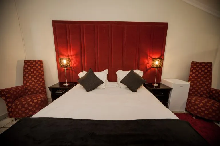 Bedroom with a large bed red headboard and matching armchairs on either side