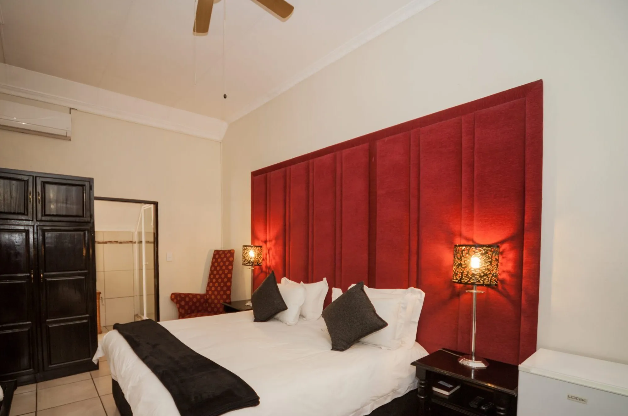 Modern bedroom with red headboard black and white bedding and bedside lamps